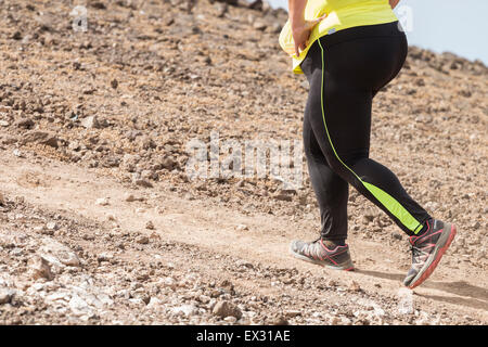 Overweight female jogger competing in mountain trail race Stock Photo