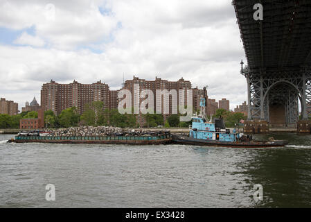 Tug and barge full of scrap metal for recycling on the East River Manhattan NYC USA . The cargo is of crushed cars for recycling Stock Photo