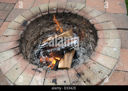 Burning wood in a garden fire pit almost ready to cook on Stock Photo