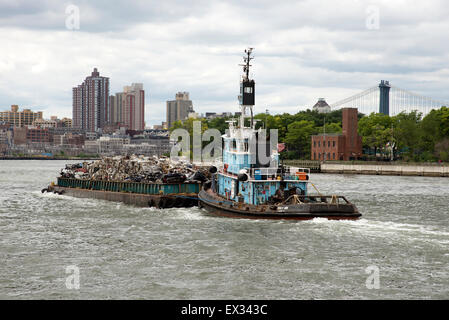 Tug and barge full of scrap metal for recycling on the East River Manhattan NYC USA . The cargo is of crushed cars for recycling Stock Photo