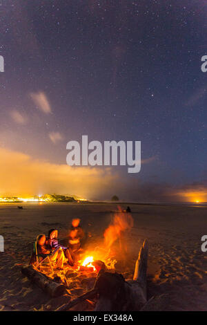 Friends gather around a beach bonfire under the stars in Cannon Beach, Oregon. Stock Photo