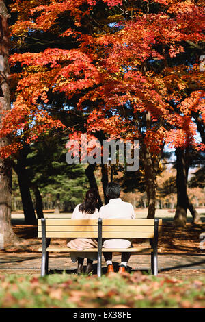 Senior Japanese couple sitting on a bench in a city park Stock Photo
