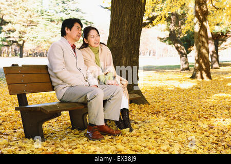 Senior Japanese couple sitting on a bench in a city park Stock Photo