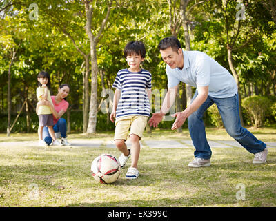 asian father teaching son to play soccer (football) Stock Photo