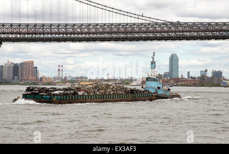 Tug and barge full of scrap metal for recycling on the East River Manhattan NYC USA . The cargo is of crushed cars for recycling Stock Photo