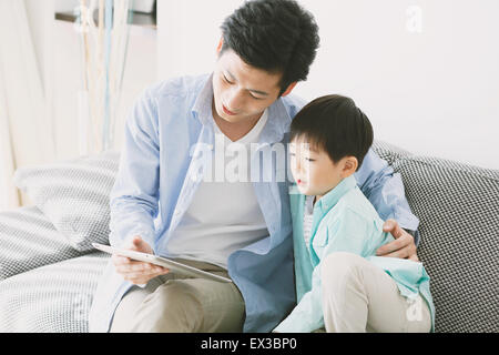 Japanese father and son on the sofa with tablet Stock Photo