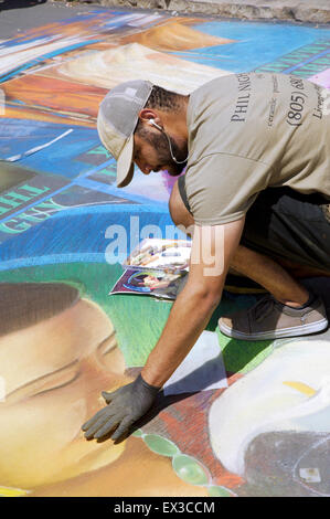 An artist is working on last touch ups on a portrait painting at the annual Imadonnari street painting festival in Santa Barbara Stock Photo
