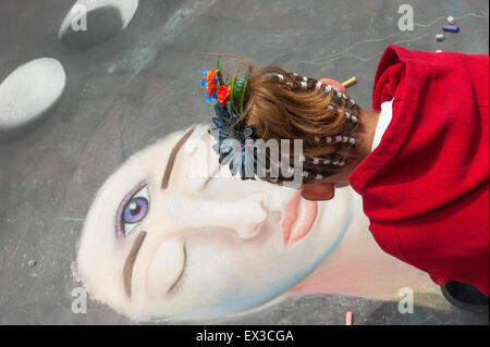 A young woman artist paints a portrait with chalk at the annual Imadonnari Street Painting Festival in Santa Barbara, CA Stock Photo