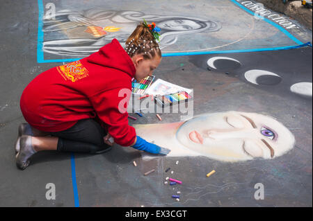 A young woman artist paints a portrait with chalk at the annual Imadonnari Street Painting Festival in Santa Barbara, CA Stock Photo