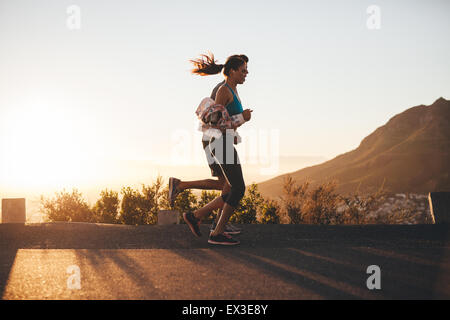 Image of young runners running together in morning. Two people jogging on a country road at sunrise. Stock Photo