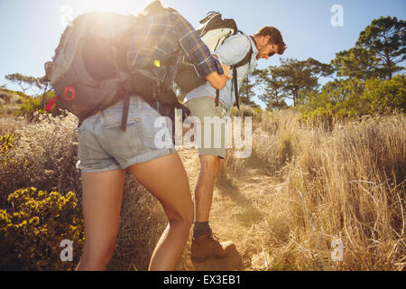 Hiker helping his girlfriend uphill in the countryside. Couple hiking in mountain on a summer day. Stock Photo
