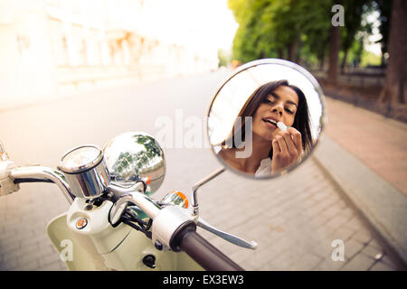 Closeup of a female applying lipstick in mirror motocycle Stock Photo