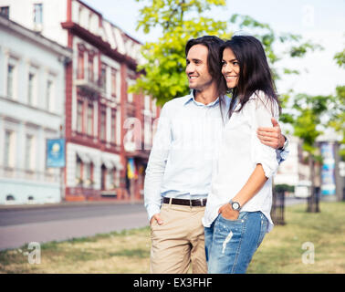 Smiling young couple standing outdoors and looking away Stock Photo