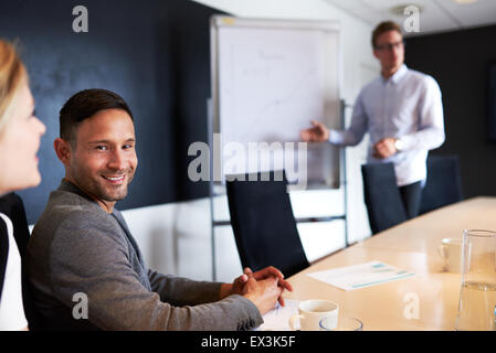 Young white male executive smiling and facing camera during work meeting