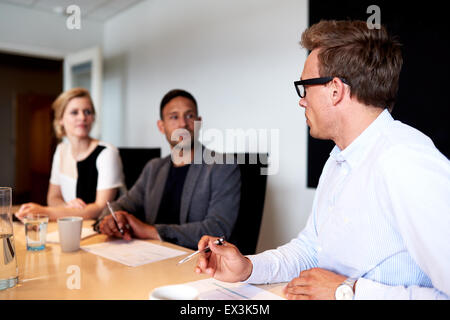 Young executives facing eachother during a meeting in conference room
