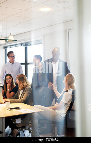 Group of young executives gathered and socializing in conference room Stock Photo