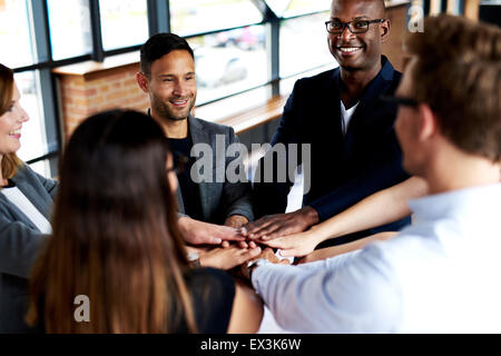 Group of young executives smiling and standing together with hands together Stock Photo