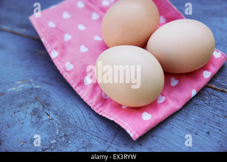 Eggs on tablecloth over wooden background Stock Photo