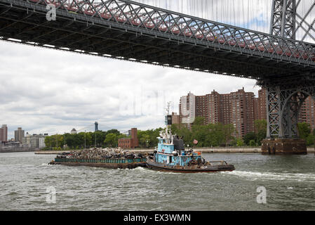 Tug and barge full of scrap metal for recycling on the East River Manhattan NYC USA . The cargo is of crushed cars for recycling Stock Photo