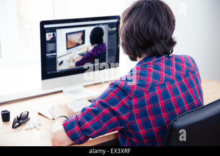 Back view portrait of a male photo editor working on computer in office Stock Photo