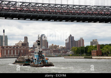 Tug and barge full of scrap metal for recycling on the East River Manhattan NYC USA . The cargo is of crushed cars for recycling Stock Photo