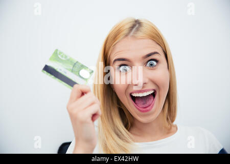 Cheerful young woman holding bank card over gray background