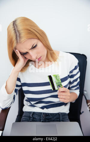 Sad casual woman holding bank card Stock Photo