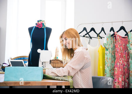 Happy beautiful woman using sewing machine in laundry Stock Photo
