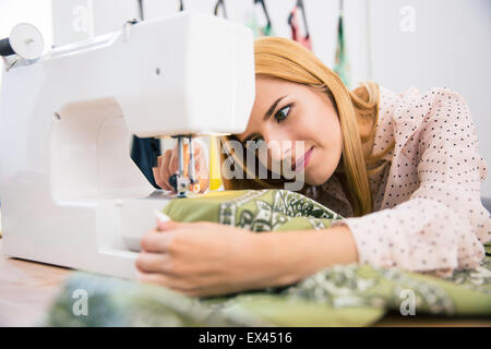 Pretty female tailor using sewing machine in laundry Stock Photo