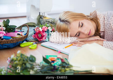 Tired fashion deisgner sleeping on the table in workshop Stock Photo