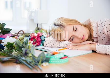 Tired female deisgner sleeping on the desk in workshop Stock Photo