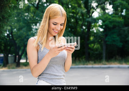 Happy young girl using smartphone outdoors Stock Photo