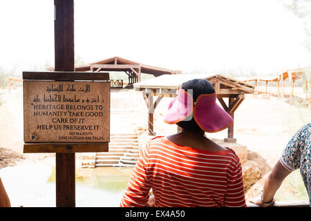 Bethany Beyond the Jordan, Jordan. Female tourist in hat in front of baptism pool. 'Heritage belongs to humanity.' Stock Photo