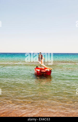 Young girl on water slide in sea life jacket vest on wearing going down waterslide Stock Photo