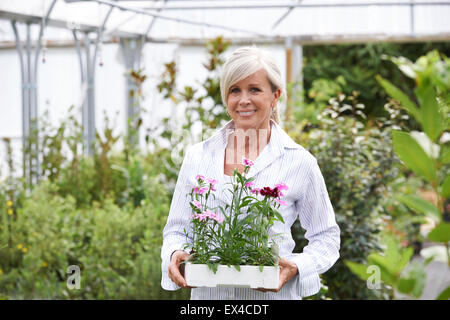Mature Woman Choosing Plants At Garden Center Stock Photo
