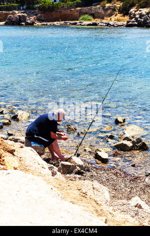 Fisherman Man fishing at waters edge baiting hook to fish river rod reel line bait Stock Photo