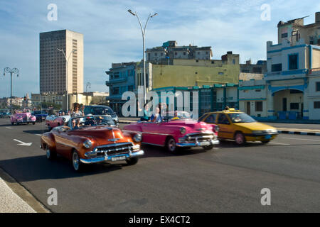 Horizontal view of classic old American cars driving along the Malecon in Havana, Cuba. Stock Photo