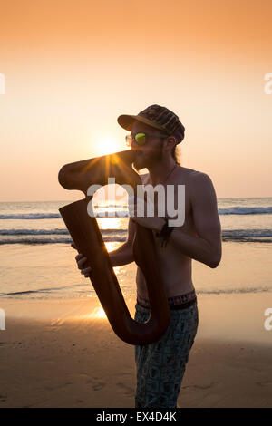 Dj playing summer hits at sunset beach party with trumpet jazz performer Stock Photo