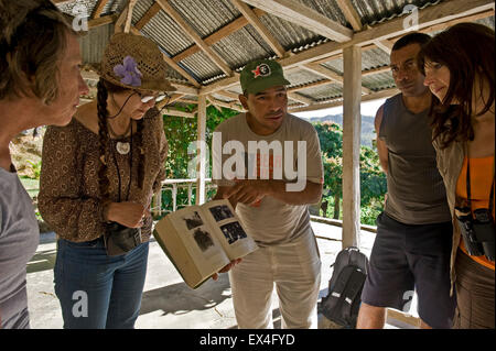 Horizontal view of a tour leader showing tourists images of Fidel Castro in a book in Turquino National Park, Cuba. Stock Photo