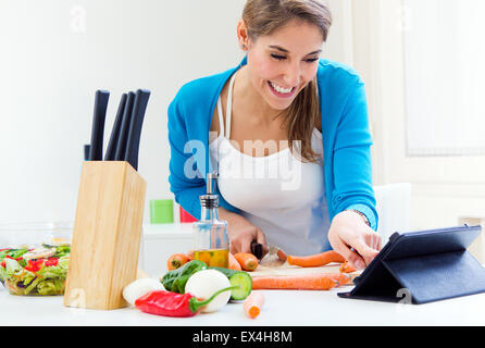 Portrait of Woman in kitchen looking for a recipe on the Internet Stock Photo