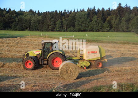 Farmer on tractor collecting and baling hay in round bales. Bavaria, Germany, Europe.  Photo by Willy Matheisl Stock Photo