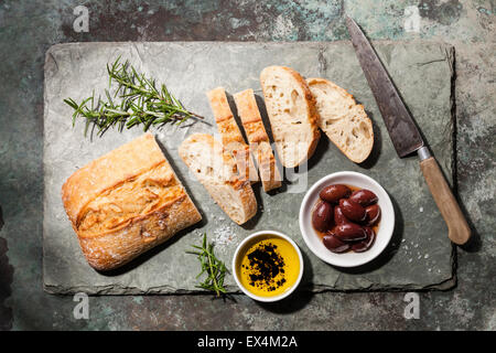 Fresh ciabatta with olive oil and olives on stone slate background Stock Photo
