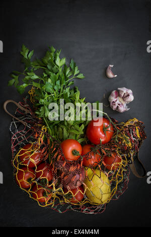Vegetables in string bag fresh from the market on slate background: Top view Stock Photo