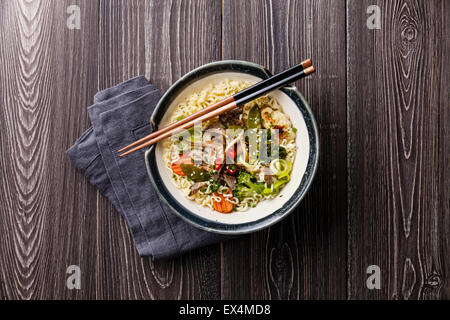 Asian noodles with oyster mushrooms and vegetables in bowl on gray wooden background Stock Photo