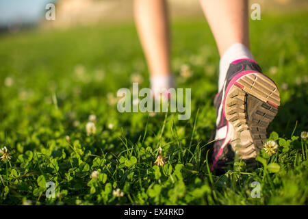 Hiker walking in the green grass outdoors, low angle close up of the foot. Stock Photo