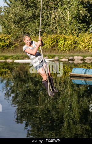 Young woman enjoying swinging on a rope swing over a farm pond in Hood River, Oregon, USA Stock Photo