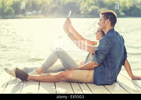 Couple in love sitting on the pier, selfie