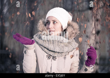 Winter beauty fashion. Joyful face girl gesturing with trendy fur hat covering her eyes on a snowy day. Emotions. High fashion portrait winter scenery. Stock Photo