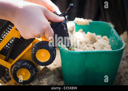 child playing with digger truck in sand pit Stock Photo