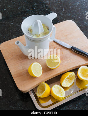 Ceramic lemon squeezer and jug designed by Conran on wooden choopping board with halved lemons Stock Photo